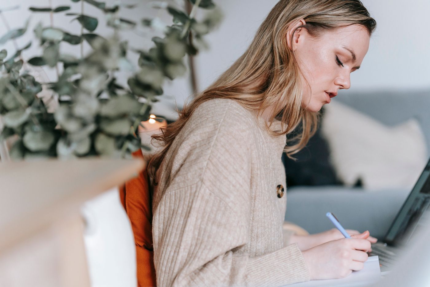 A woman writing in a notebook beside her laptop