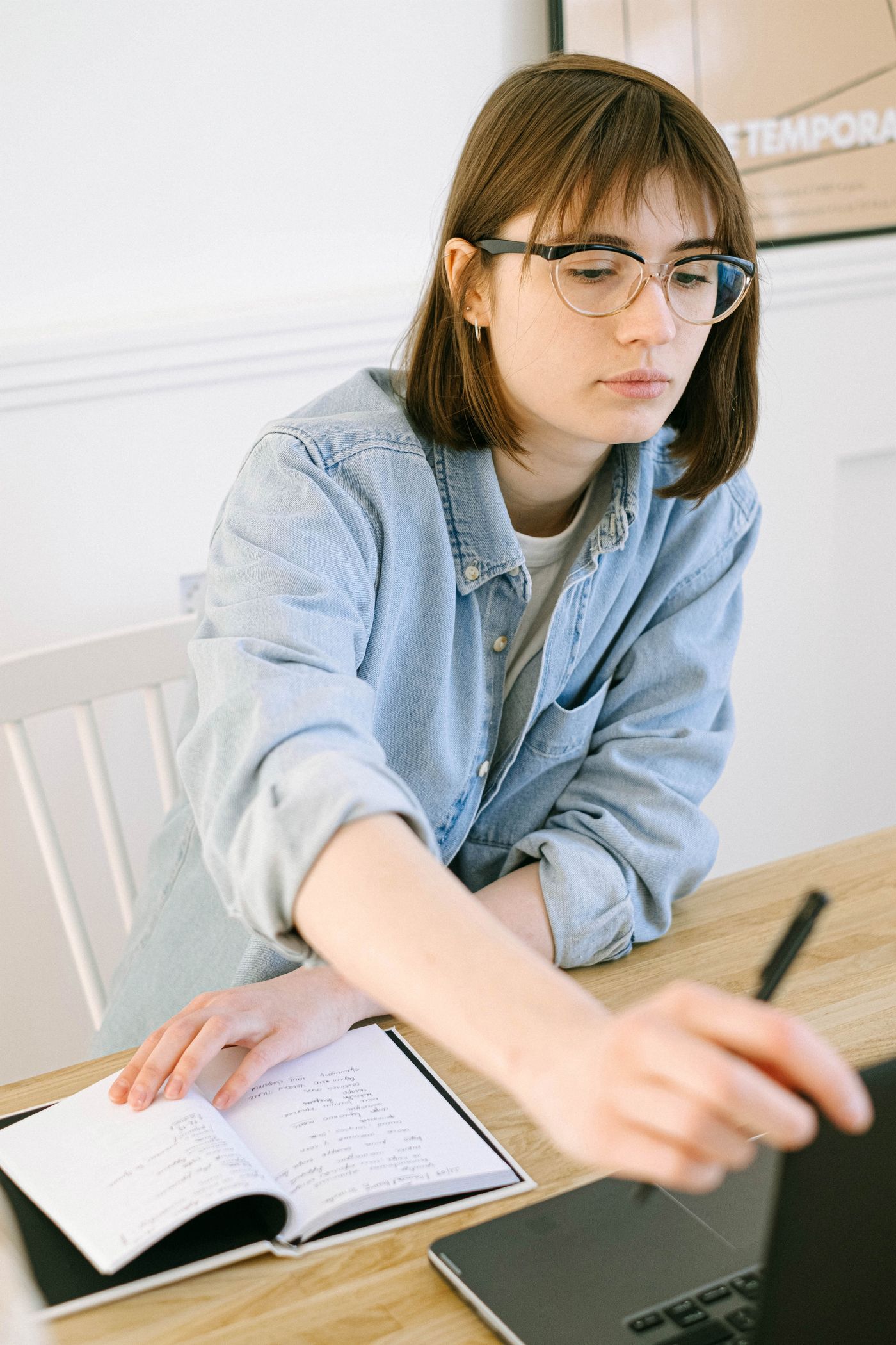 A woman using a laptop and taking notes at a desk