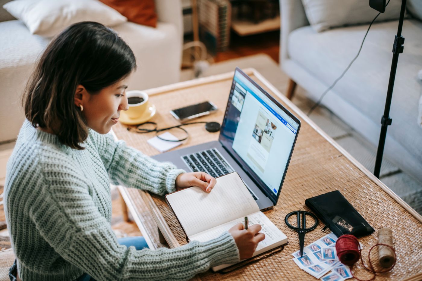 A woman organising notes and using a laptop at home